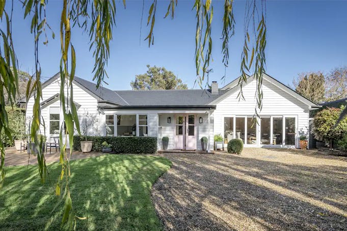 A larger white house with a garden and driveway.